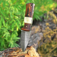 Damascus steel blade skinning knife with rosewood and bone handle, razor-sharp edge, and leather sheath.
