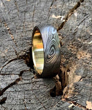 Close-up of a Damascus steel ring with brass inlay